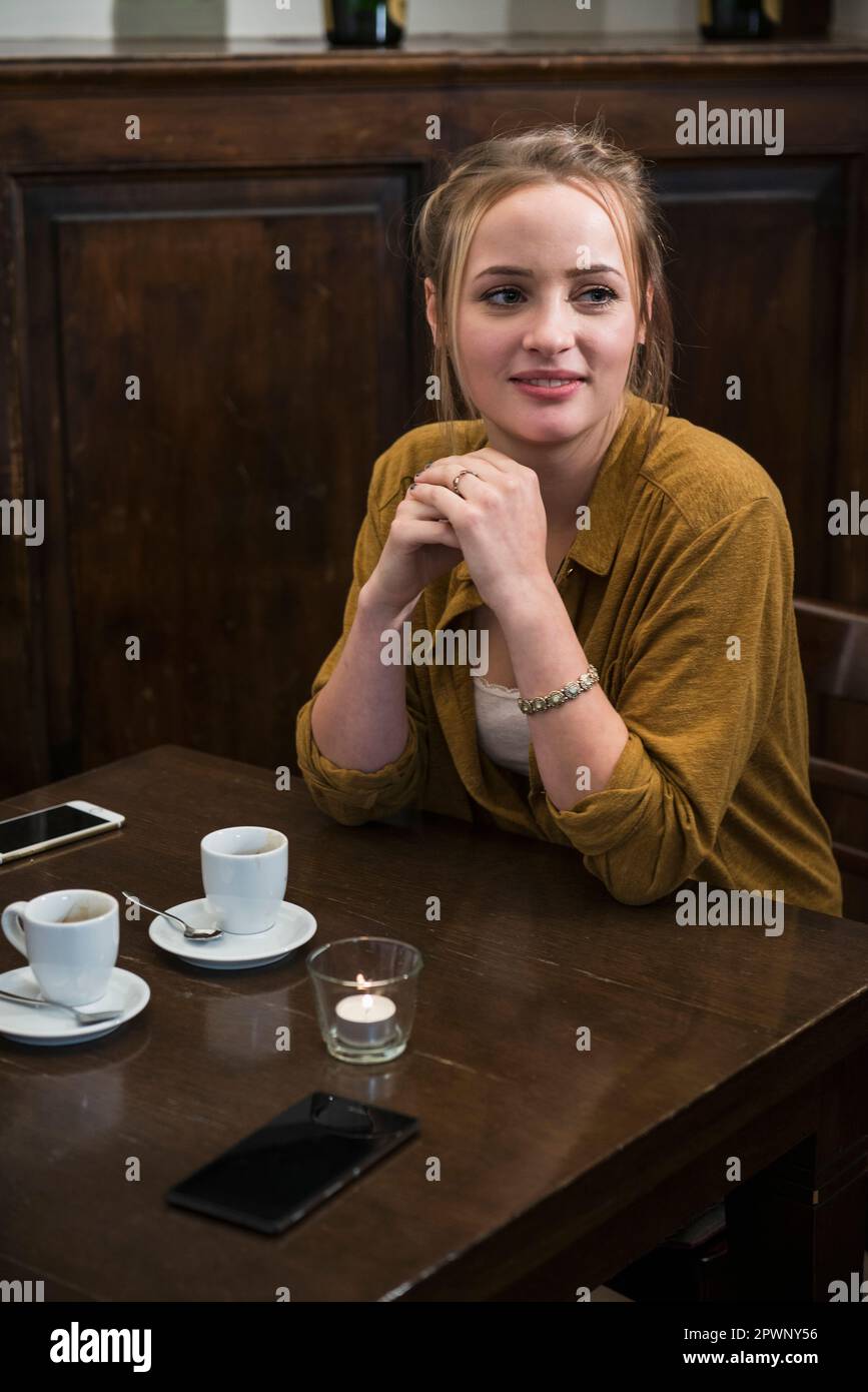 Jeune femme assise près d'une table à manger au restaurant Banque D'Images