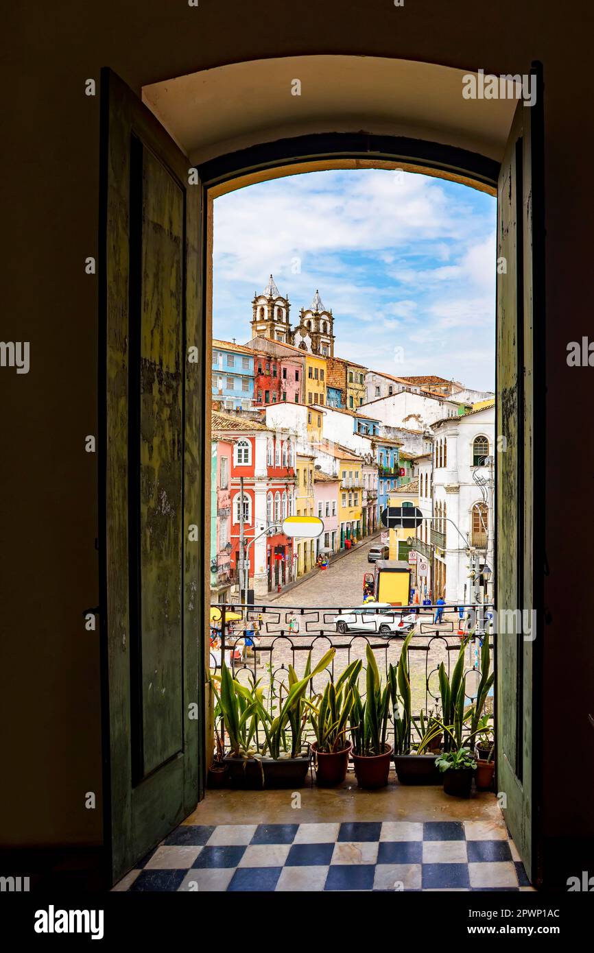 Une porte ouverte dans une ancienne maison coloniale donnant sur le quartier de Pelourinho et ses collines à Salvador, Bahia Banque D'Images