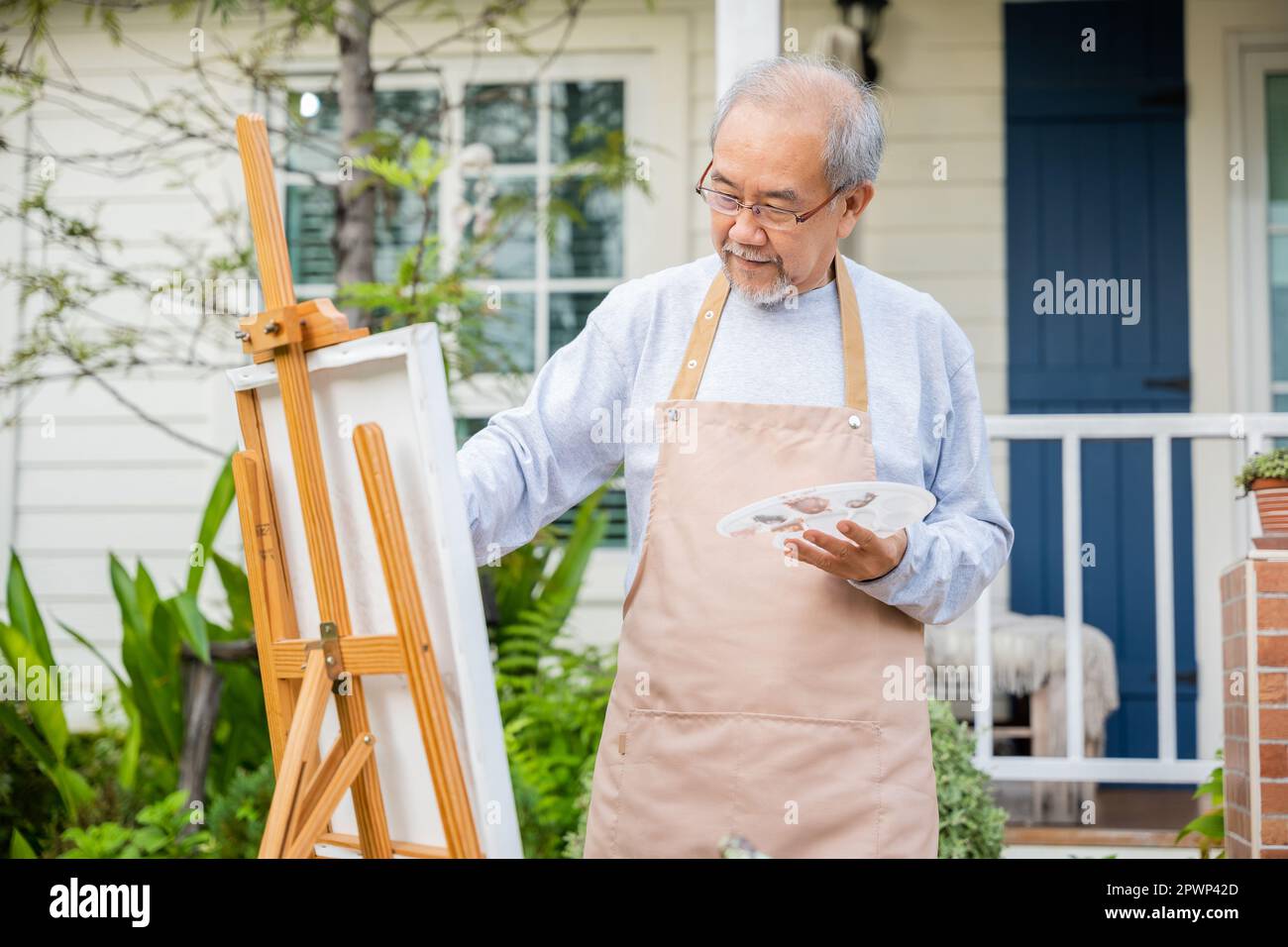 Style de vie asiatique senior homme de la peinture de l'art d'image en utilisant la couleur de pinceau et d'huile sur la toile, les personnes âgées sourient la peinture à son chevalet à l'extérieur vert nat Banque D'Images