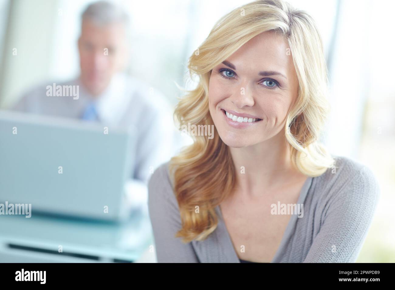 Elle est passionnée par sa carrière. Portrait court d'une femme d'affaires blonde attrayante avec un collègue en arrière-plan. Banque D'Images