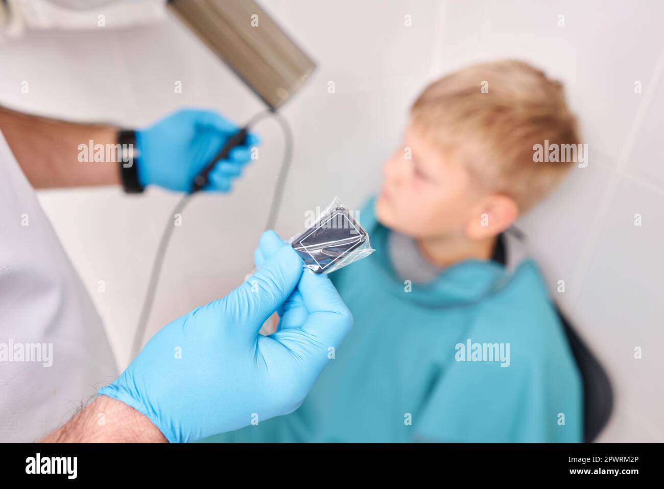 Médecin pointant l'appareil à rayons X tenant le capteur électronique chez l'enfant. Le dentiste prépare le garçon à une radiographie des dents en clinique dentaire. Banque D'Images