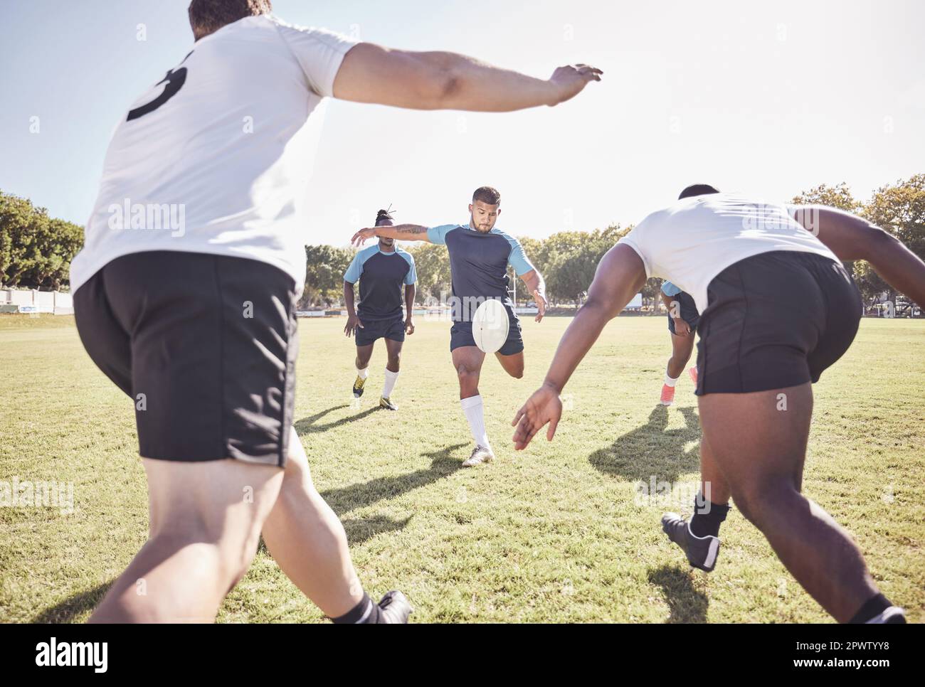 Joueur de rugby de course mixte essayant un dropkick pendant un match de rugby à l'extérieur sur le terrain. Homme hispanique qui donne un coup de pied ou tente de marquer trois p Banque D'Images