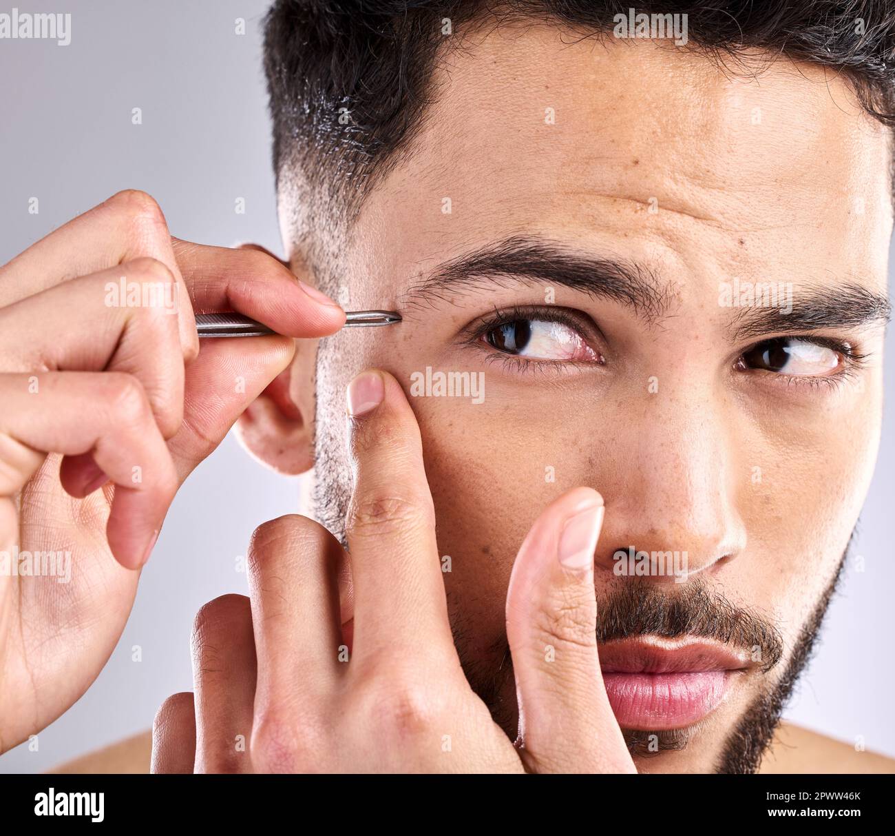 Je n'aime pas quand les choses sont à l'écart. Gros plan d'un jeune homme  en brossant ses sourcils sur un fond gris Photo Stock - Alamy