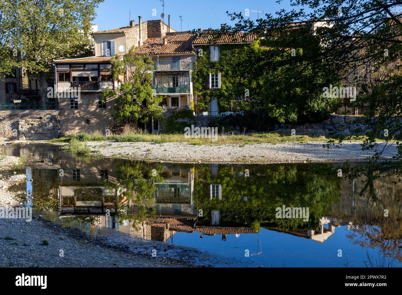 Réflexion de bâtiments sur les rives de la Cesse dans le village français de Bize-Minervois Banque D'Images