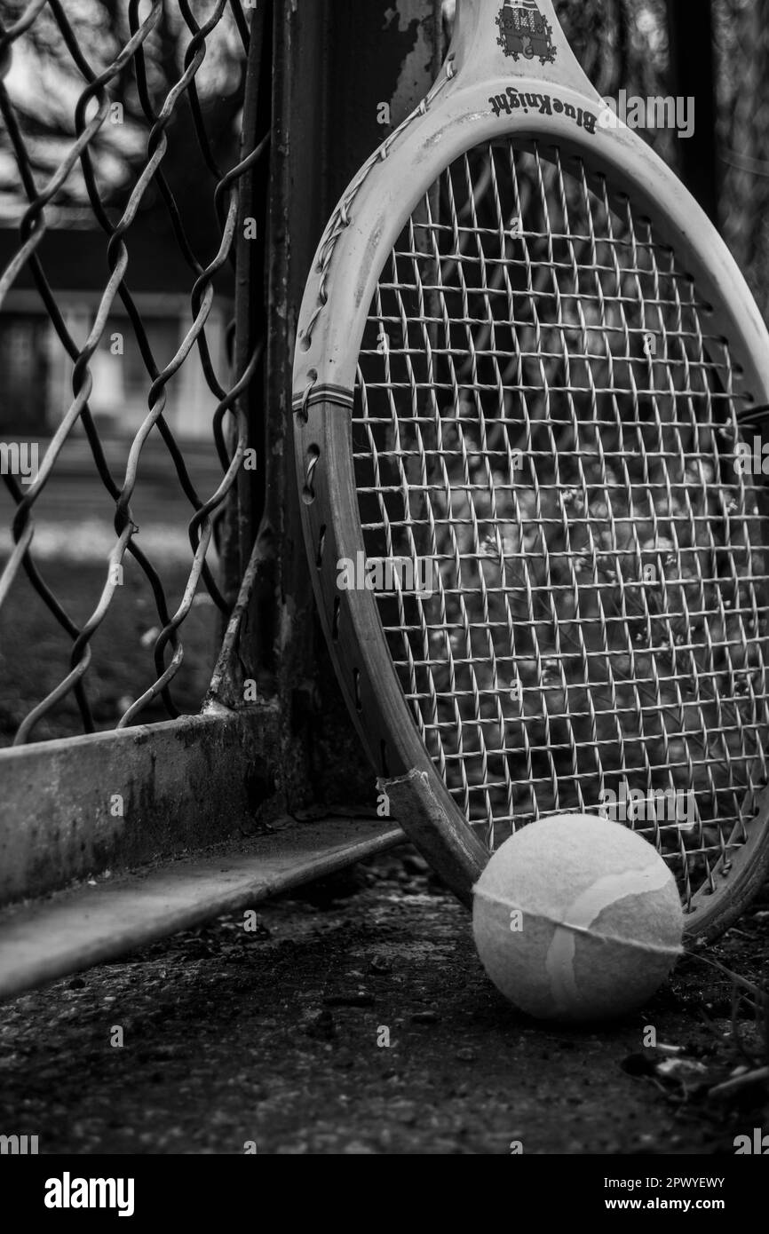 Raquette de tennis et balle contre une clôture dans un parc Banque D'Images