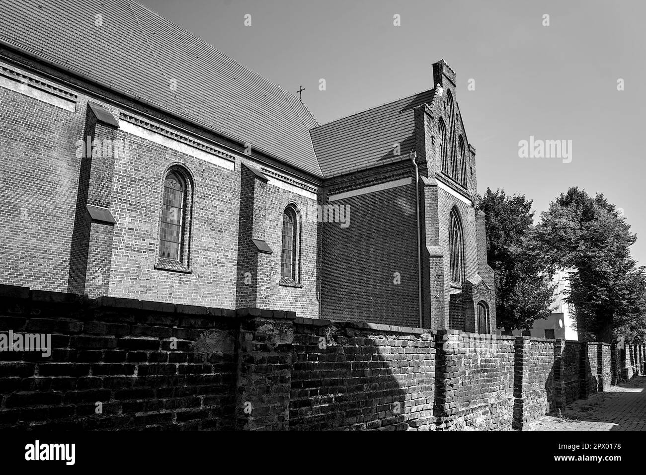 Le mur et l'église historique en brique rouge dans le village de Bledzew en Pologne, monochrome Banque D'Images