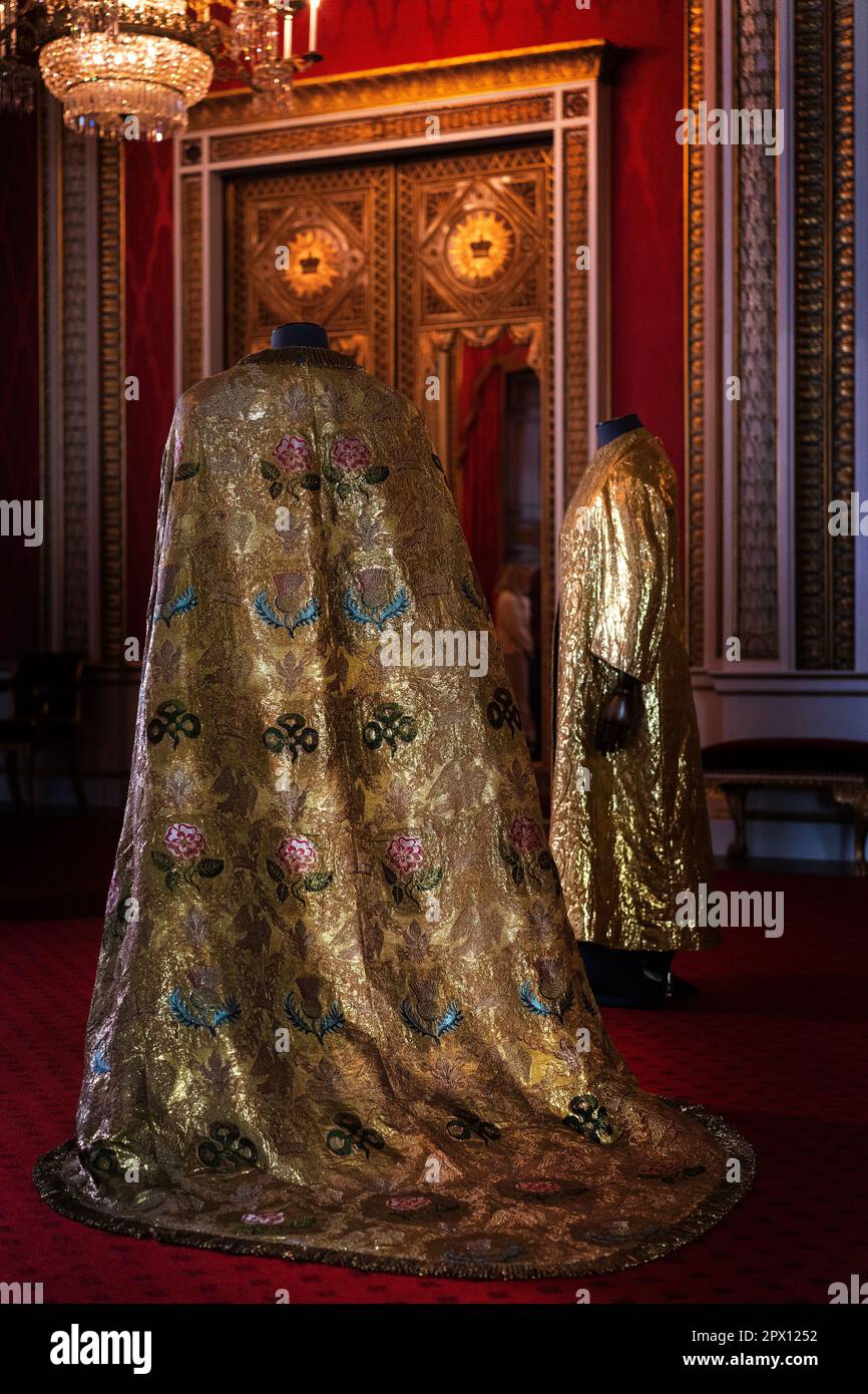 Les vêtements de Coronation, comprenant le manteau impérial (à gauche) et la Supertunica (à droite), exposés dans la salle du Trône à Buckingham Palace, Londres. Les vêtements seront portés par le roi Charles III lors de son couronnement à l'abbaye de Westminster sur 6 mai. Date de la photo: Mercredi 26 avril 2023. Banque D'Images
