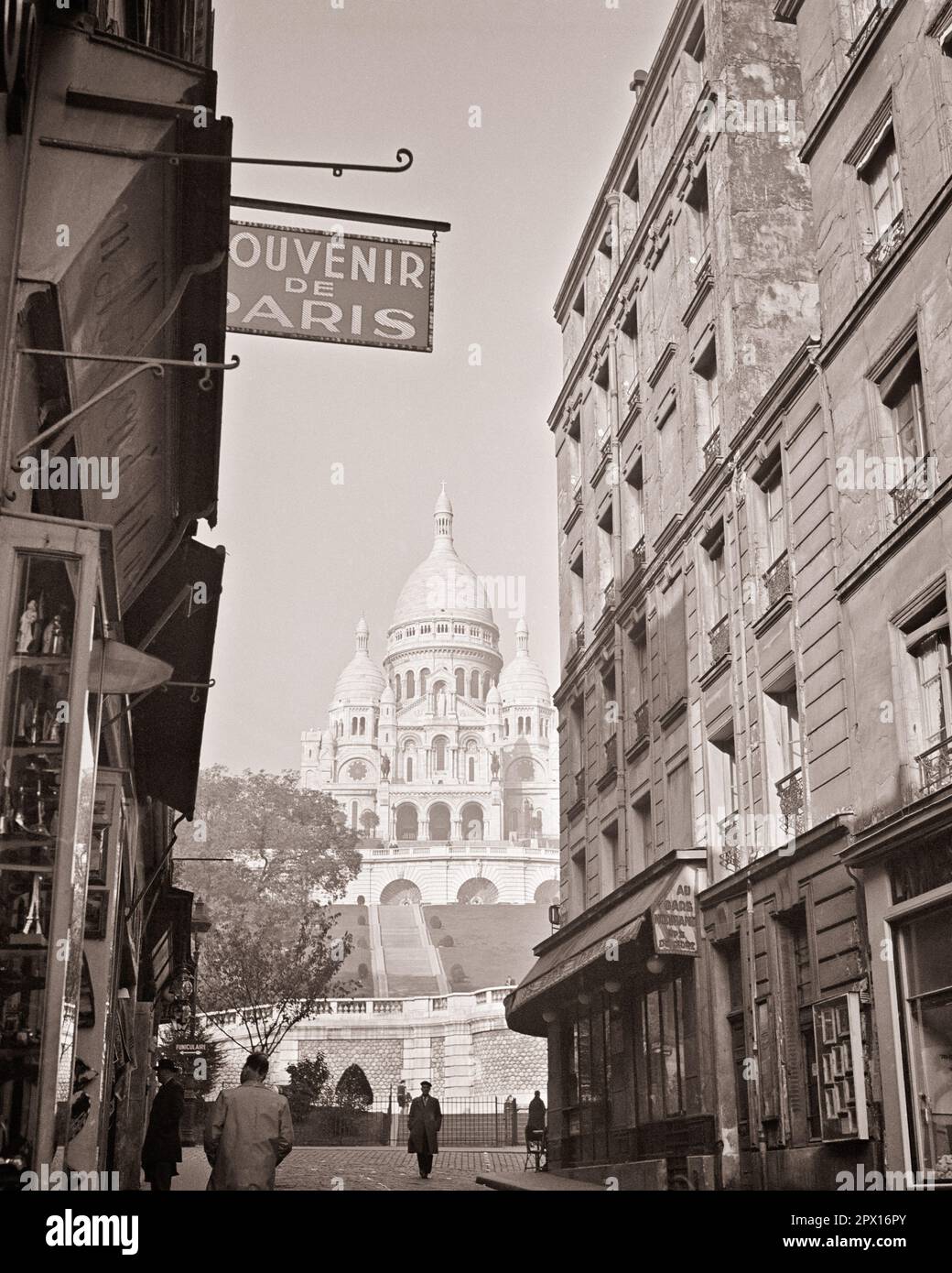 1950S 1960S ENSEIGNE SOUVENIR AU PIED DE LA COLLINE À LA RECHERCHE DE LA BASILIQUE SACRÉ-CŒUR AU SOMMET DE MONTMARTE LE POINT CULMINANT DE LA VILLE DE PARIS FRANCE - R3119 HAR001 HARS FIDÈLE ROMAIN CATHOLIQUE COEUR FOI SPIRITUELLE ATTRACTION TOURISTIQUE BASILIQUE CROYANCE NOIR ET BLANC HAR001 SITE D'INSPIRATION TOURISTIQUE À L'ANCIENNE Banque D'Images