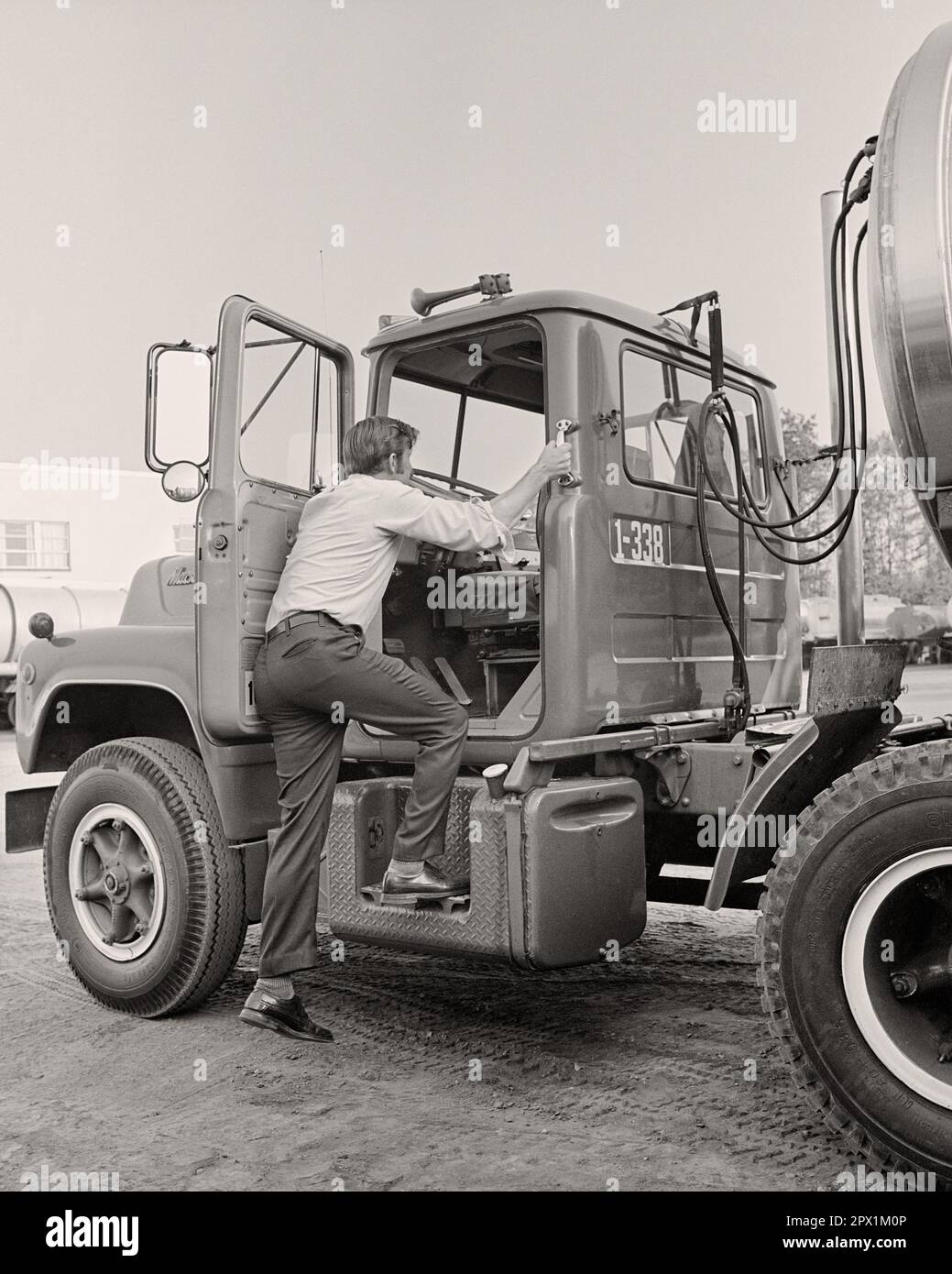 1970S VUE ARRIÈRE DU CONDUCTEUR DE CAMION QUI MONTE DANS LA CABINE DE SON VÉHICULE DE TRANSPORT DE PRODUITS CHIMIQUES EN VRAC - M9608 HAR001 HARS COMPÉTENCES AVENTURE CHIMIQUE SON CAMION DE SERVICE À LA CLIENTÈLE MAIN-D'ŒUVRE ANGLE BAS VUE ARRIÈRE VERS LE HAUT EMPLOIS DE DERRIÈRE LES VÉHICULES GROS VUE ARRIÈRE DE L'EMPLOYÉ DE RIG HOMME ADULTE MOYEN-ADULTE FEMME SEMI-CAMIONNAGE JEUNE ADULTE HOMME NOIR ET BLANC RACE BLANCHE HAR001 LE TEMPS PASSÉ Banque D'Images