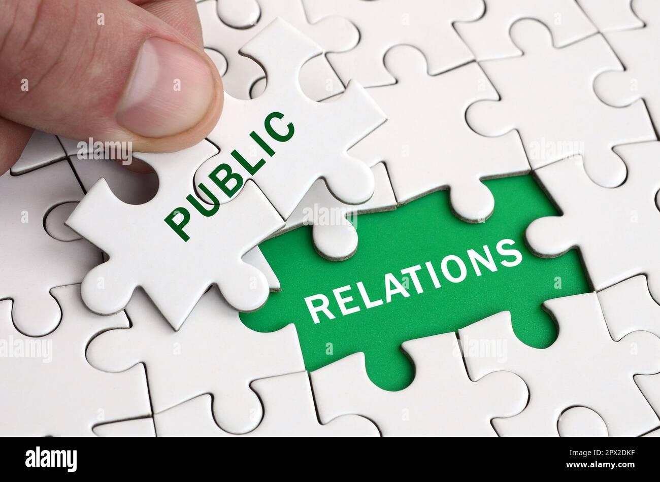 La main de l'homme remplit les derniers éléments manquants de la surface du casse-tête. Avec des mots de l'image et les relations publiques Banque D'Images