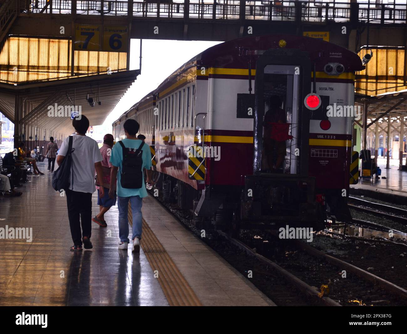 Les gens marchent jusqu'à un train qui attend sur une plate-forme à la gare de Hua Lampong, Bangkok, Thaïlande. Bien que de nombreux trains aient déménagé à une nouvelle gare dans le nord de la ville certains trains circulent encore de la gare de Hua Lampong, Banque D'Images