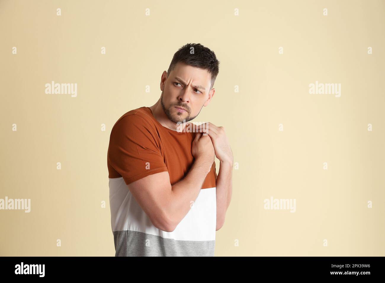 Homme gourmand qui cache quelque chose sur fond beige Photo Stock - Alamy