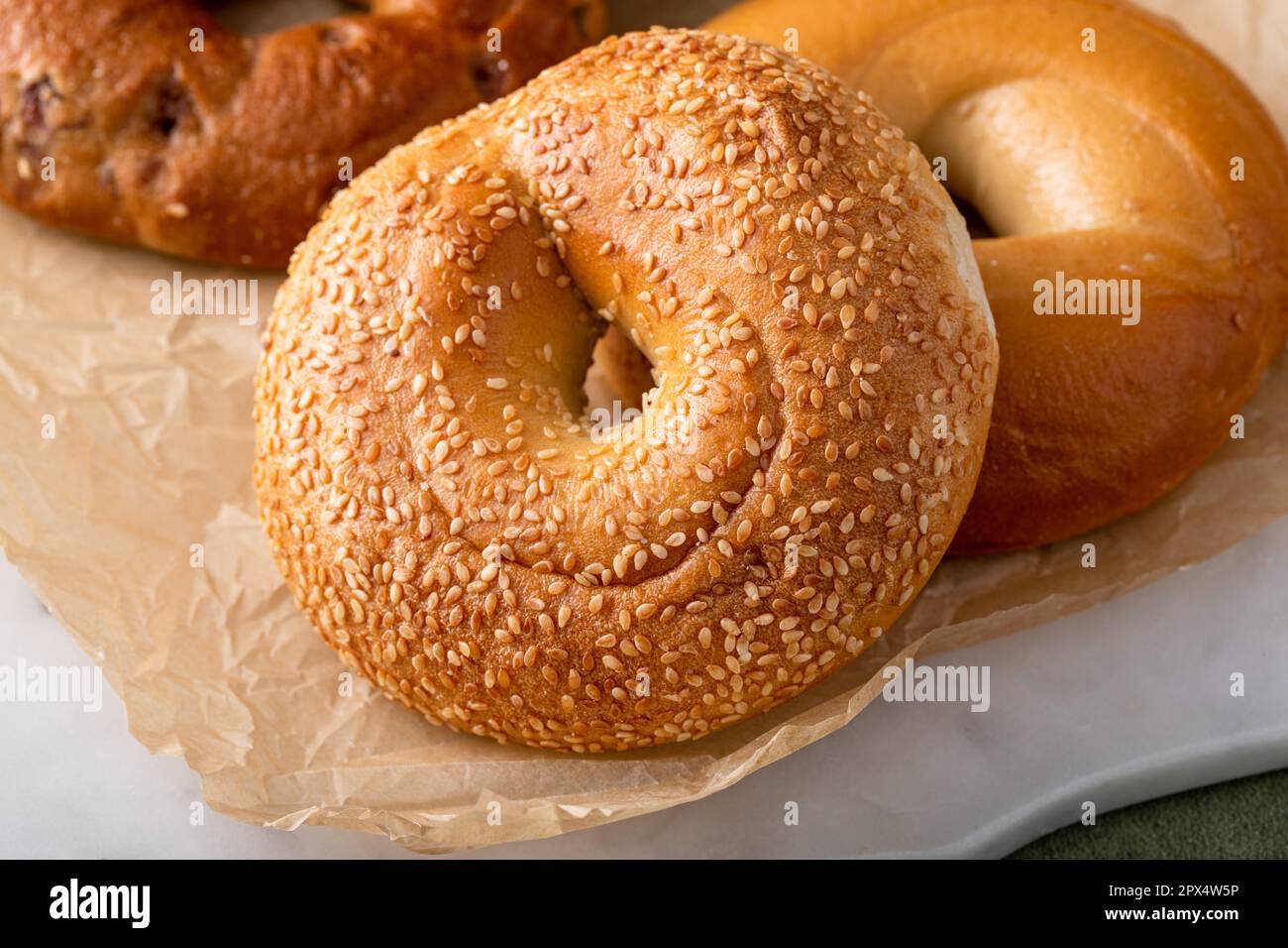 Bagels maison fraîchement cuits sur un papier parchemin prêt à manger, raisins secs de cannelle, sésame et bagel simple Banque D'Images