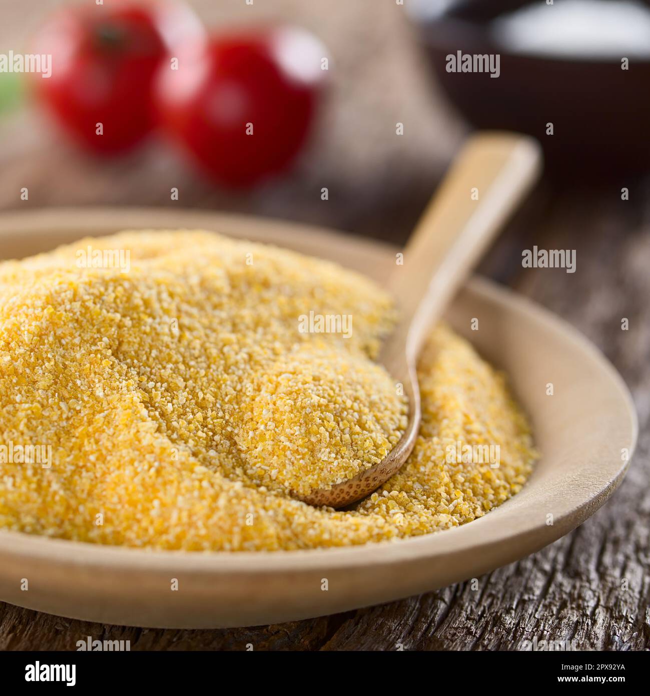 Semoule de maïs ou polenta grossièrement broyée sur une plaque en bois avec une cuillère en bois