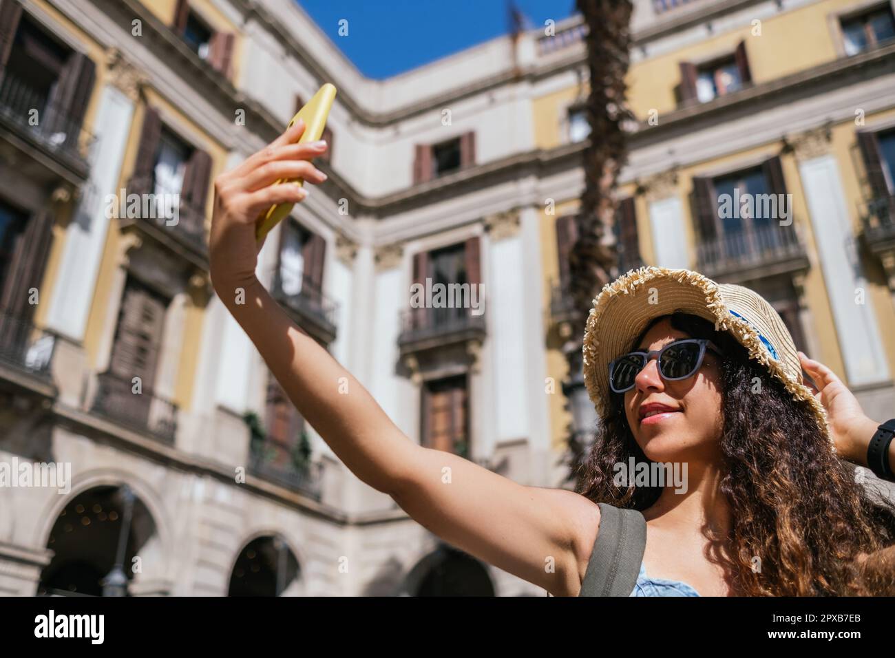 jeune touriste indienne portant un chapeau de paille et des lunettes de soleil prenant une photo de soi à la place de la ville Banque D'Images