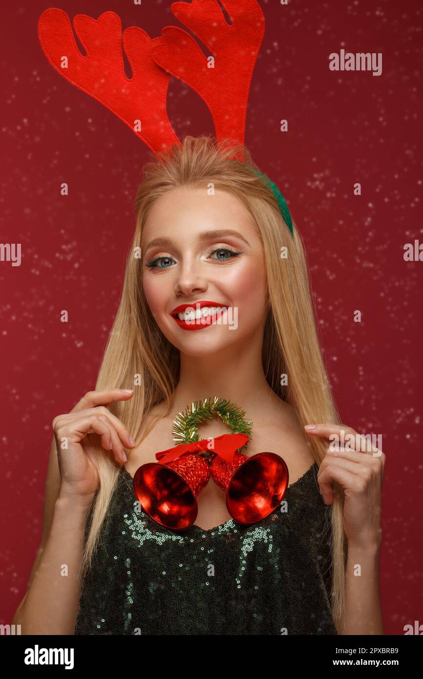 Belle fille blonde dans une nouvelle image de l'année avec Noël cloches autour du cou et les cerfs cornes sur sa tête. Beauté Visage avec le maquillage de fête. Ta photo Banque D'Images