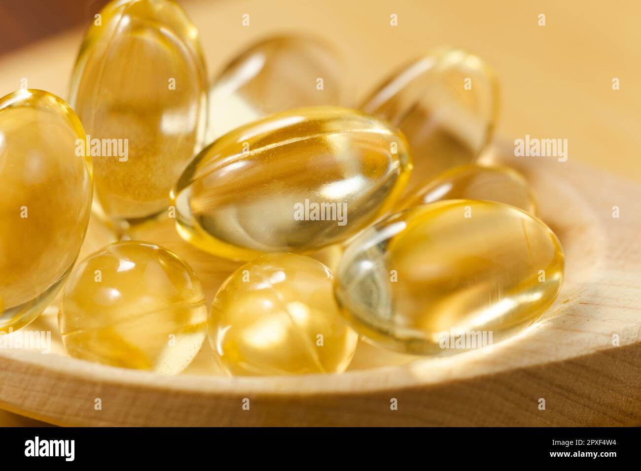 Capsules de gel doux à l'huile jaune sur fond en bois. Capsule cosmétique de pilule de vitamine E, A, huile d'amande, Omega 3, poisson. Banque D'Images