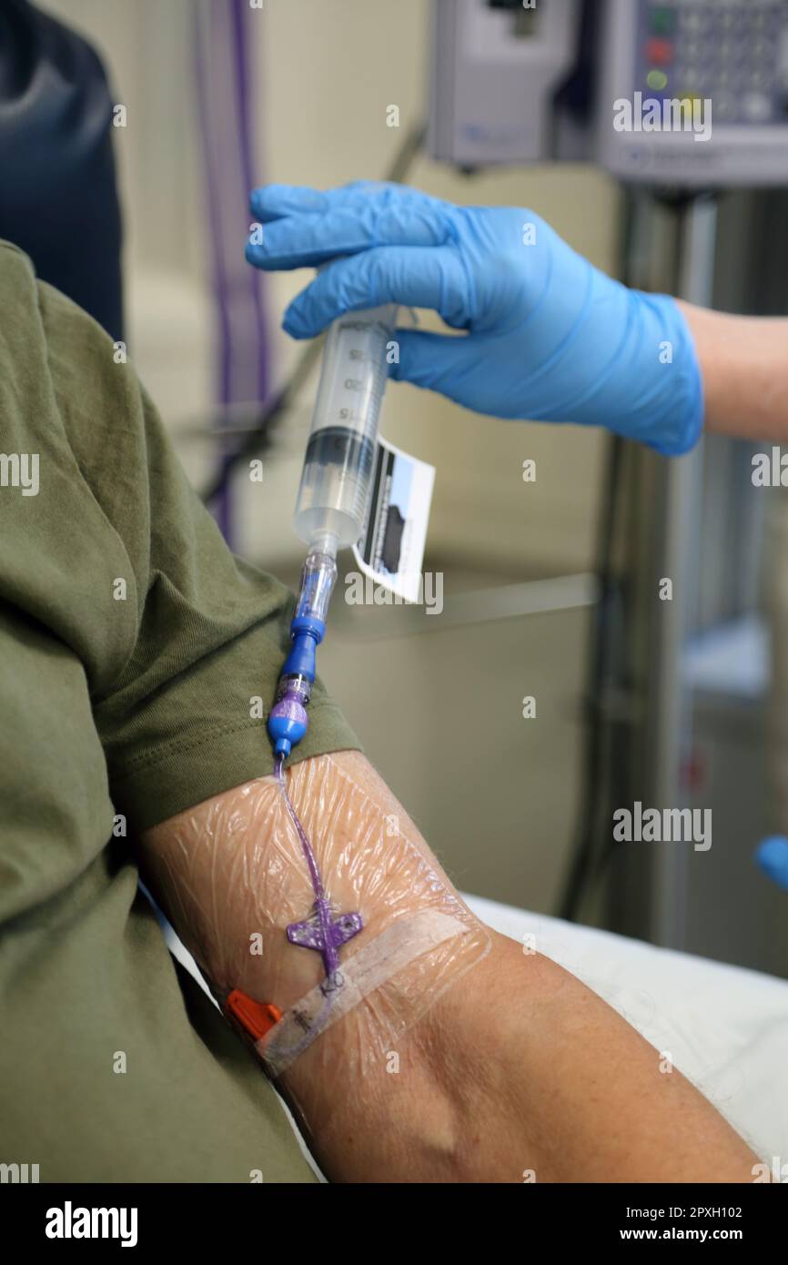 Le médicament de chimiothérapie Fluorouracile étant injecté dans la ligne Picc de la patiente de cancer masculine à l'hôpital Surrey, en Angleterre Banque D'Images