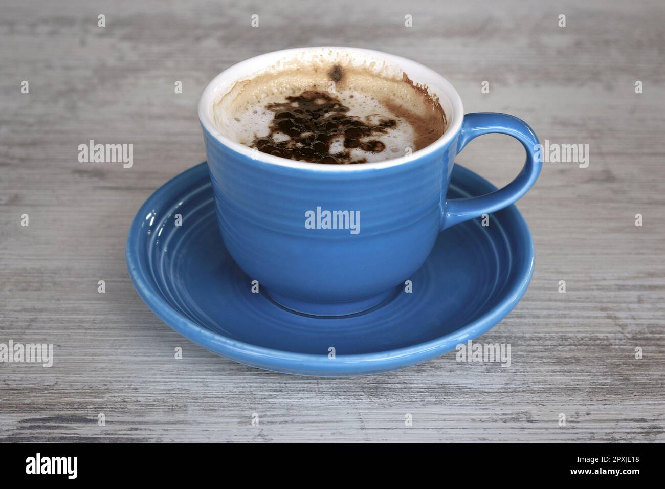 Une tasse de cappuccino bleu sur une table en bois gris. Banque D'Images