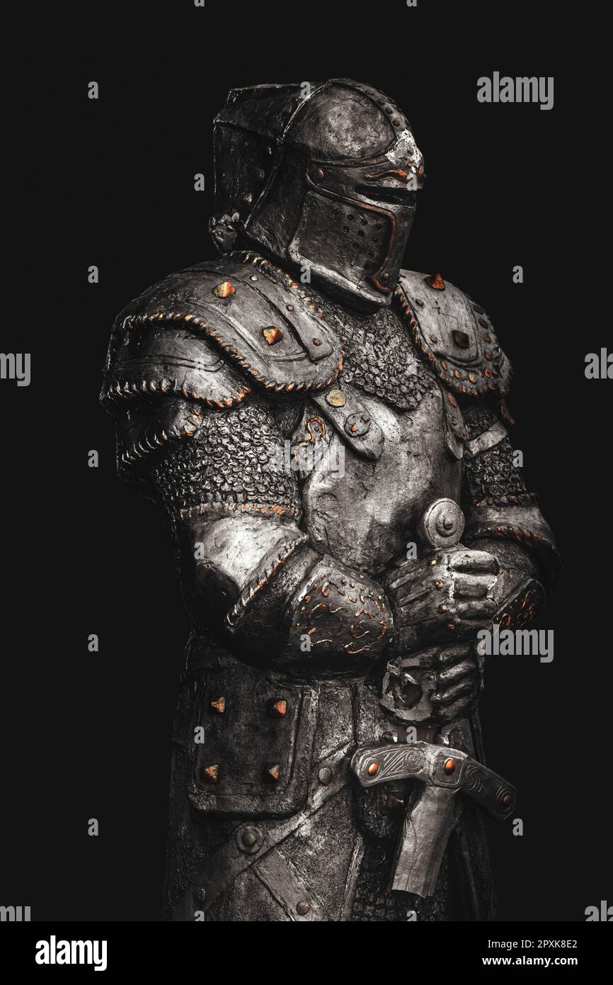 Statue de chevalier médiéval en armure métallique avec une épée, isolée sur fond noir foncé, foyer sélectif Banque D'Images