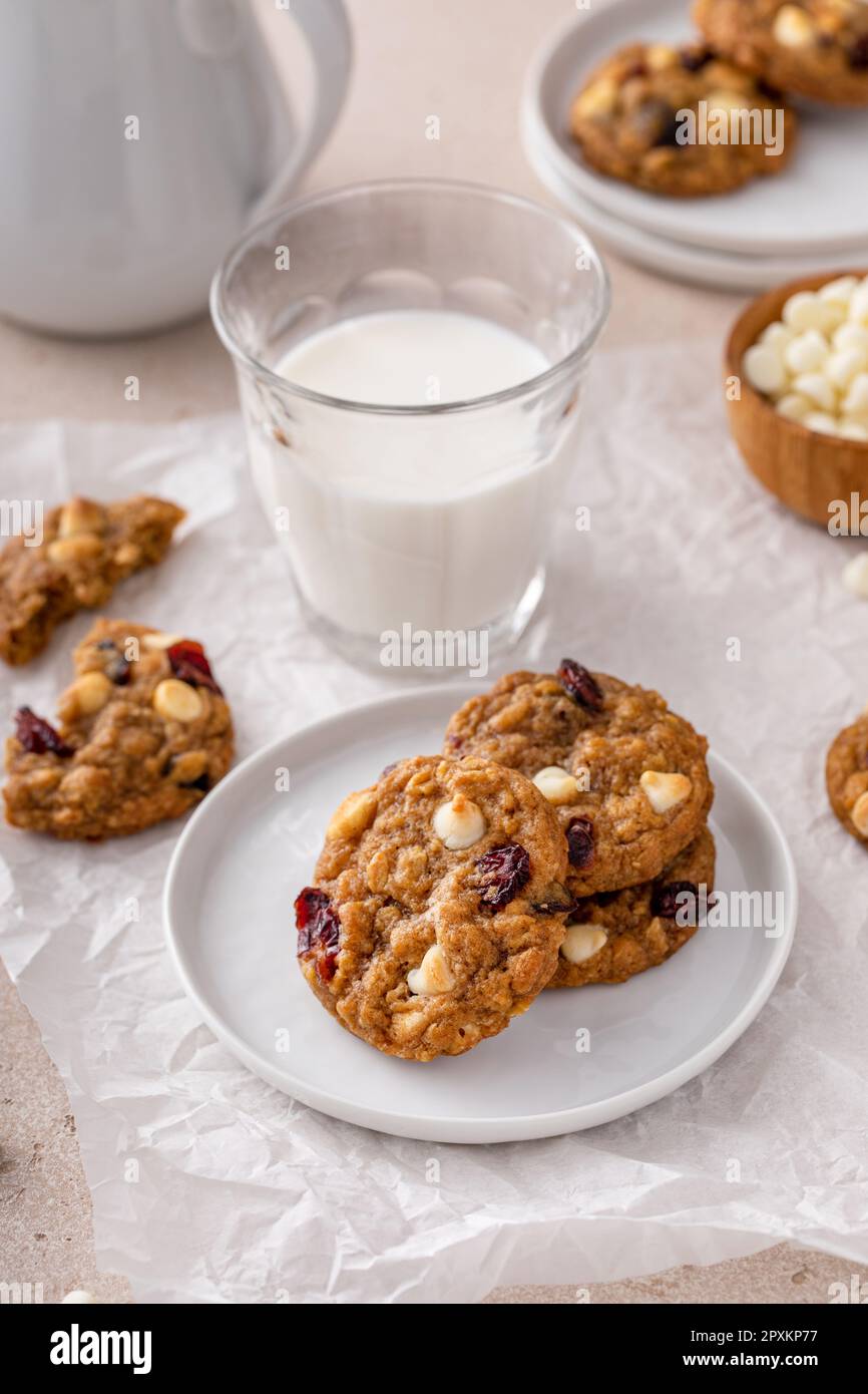 Biscuits au chocolat blanc et aux canneberges sur une assiette blanche avec un verre de lait Banque D'Images