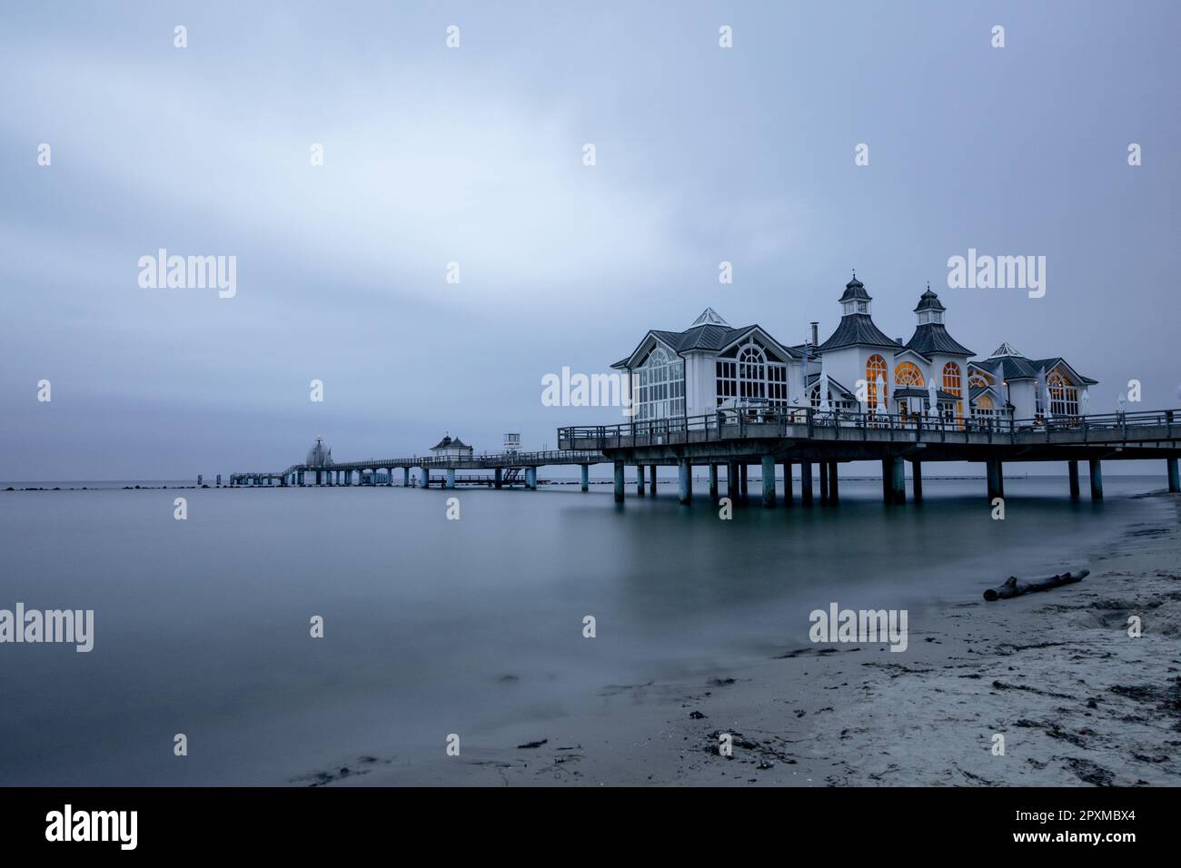 Un restaurant extérieur situé sur une jetée en bois au bord de l'eau, au crépuscule Banque D'Images
