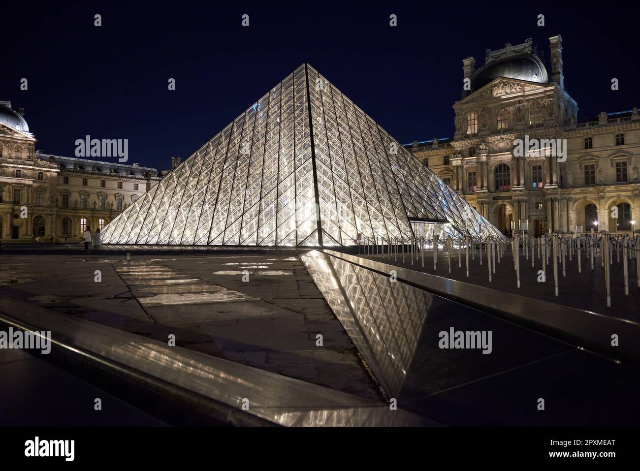 La Pyramide du Louvre brille la nuit dans une cour vide Banque D'Images