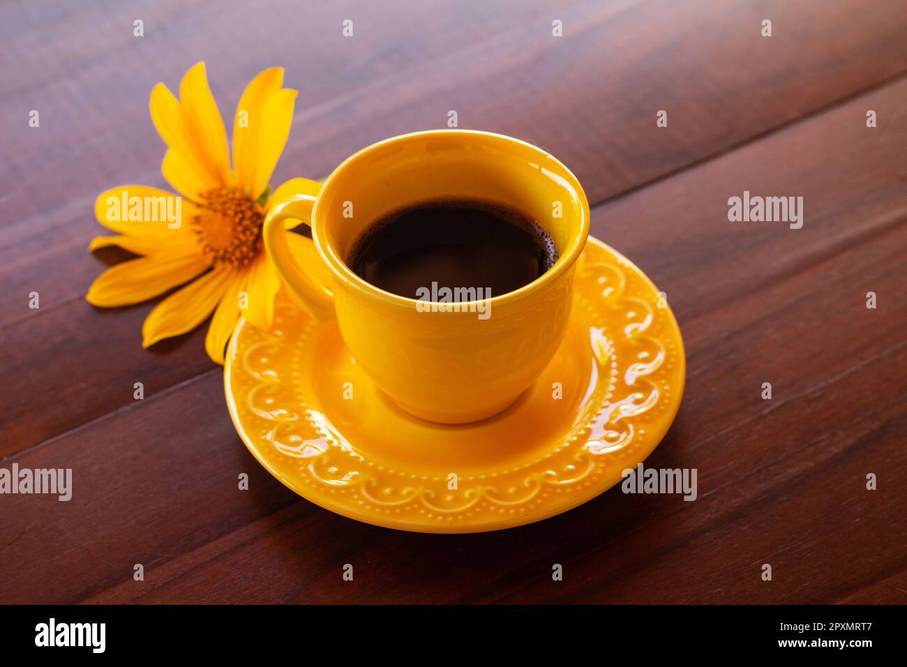 Goiania, Goias, Brésil – 01 mai 2023 : une tasse jaune avec café et un tournesol sur une table en bois. Banque D'Images