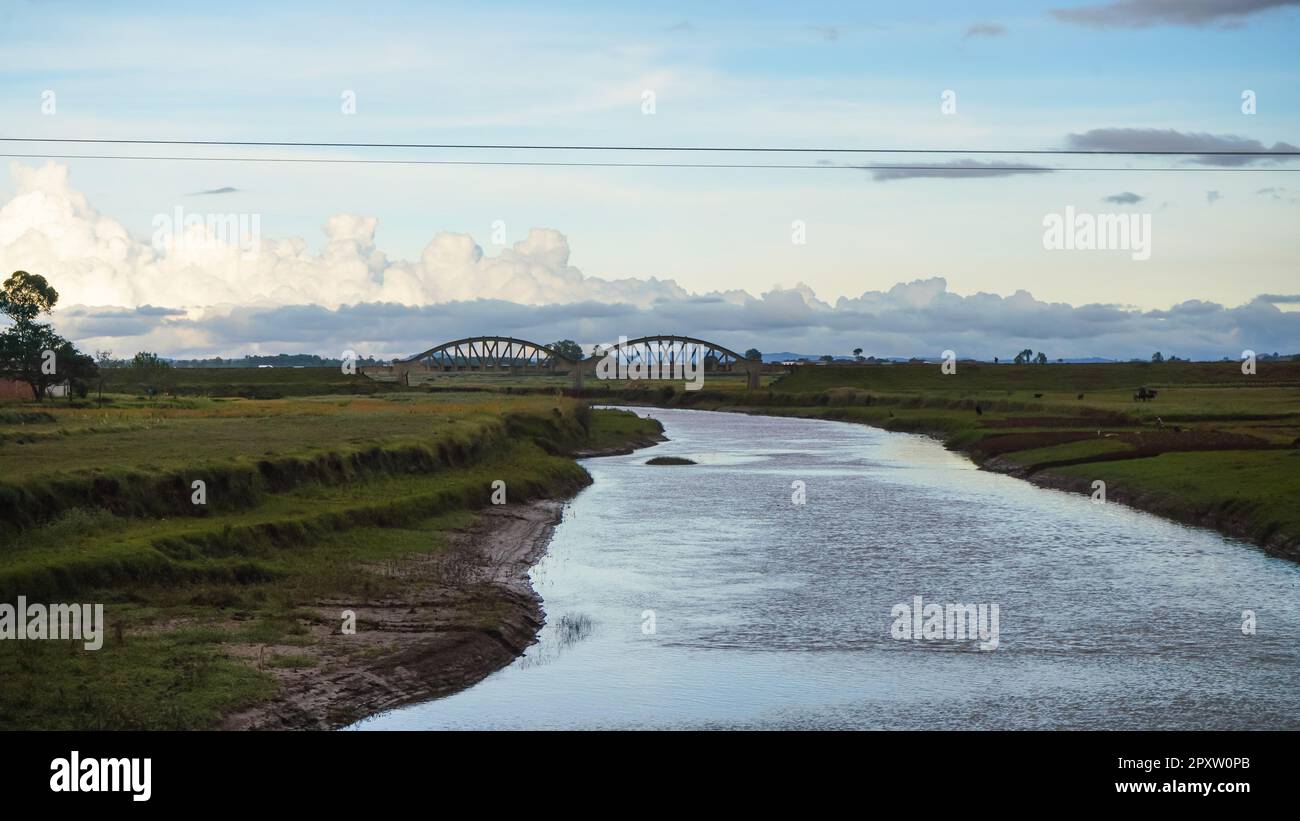 Pont ferroviaire sur petite rivière près d'Ambatolampy, Madagascar, herbe verte et arbres autour. Il n'y a que peu de chemins de fer sur toute l'île. Banque D'Images