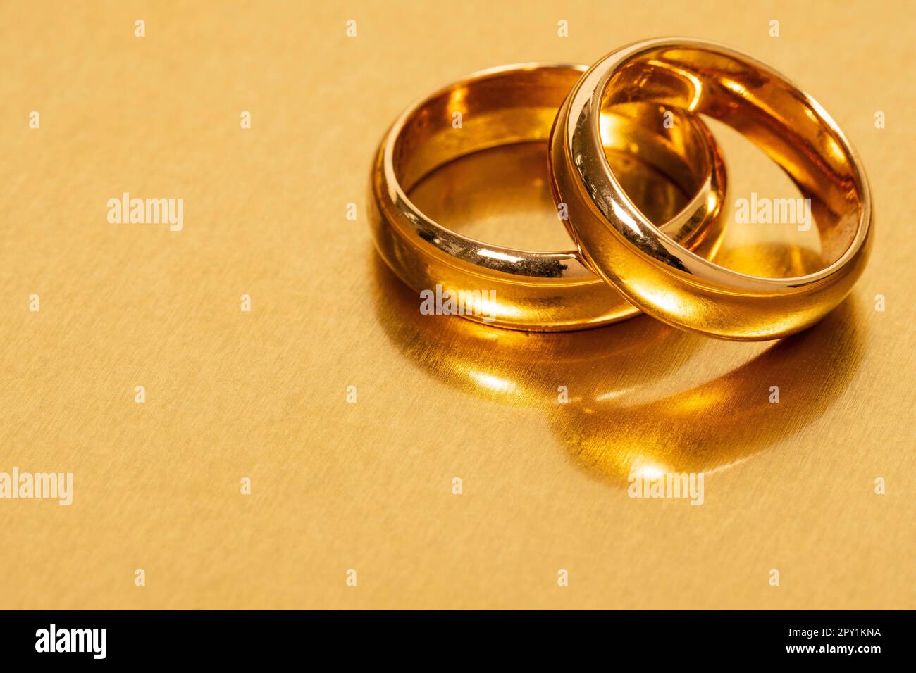 Deux anneaux de mariage dorés sur fond doré. Copier l'espace. Banque D'Images