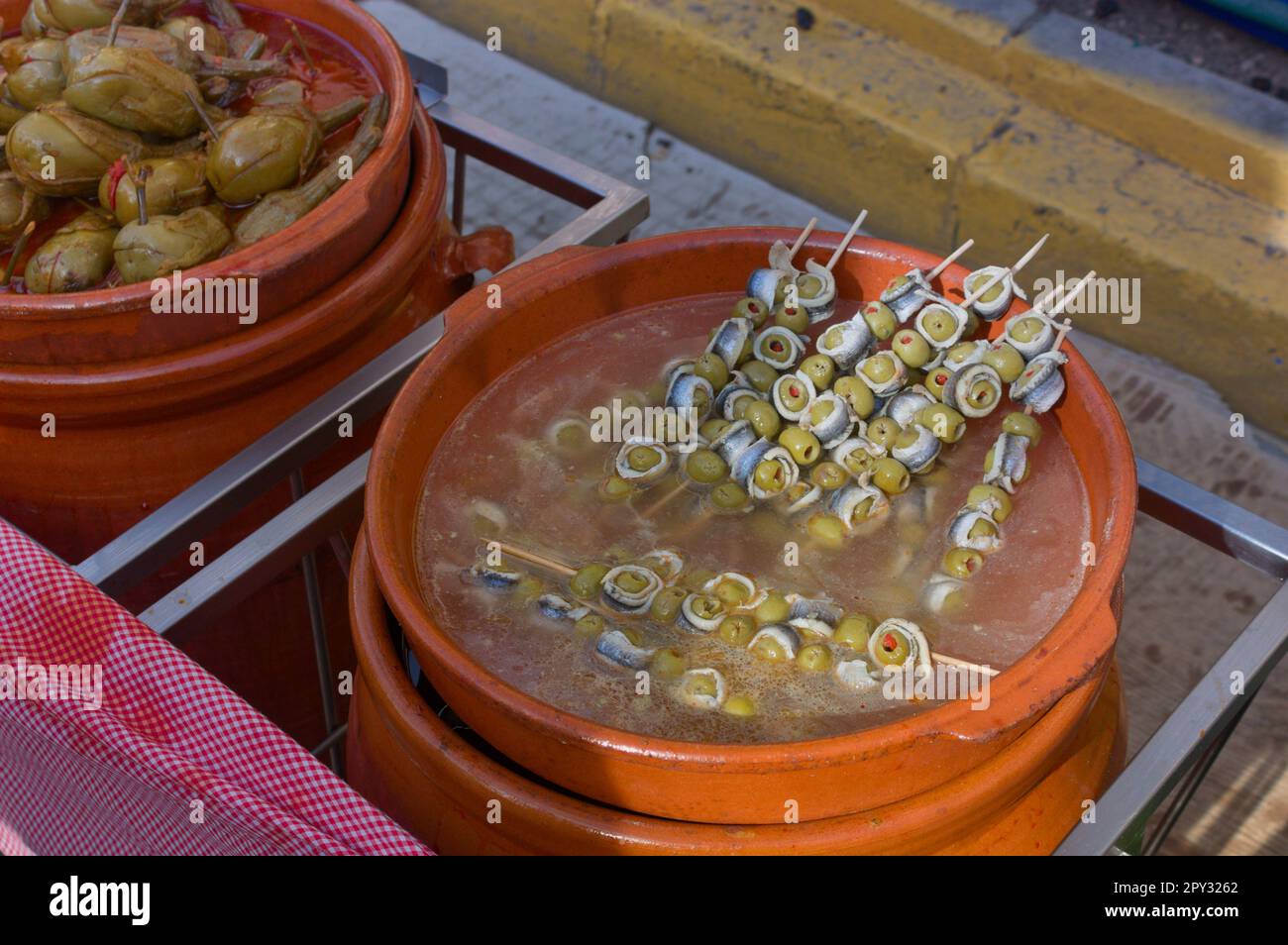 Gros plan d'un pot en céramique rempli de brochettes d'olives et de sardines marinées ou d'anchois à côté d'un autre pot rempli d'aubergines farcies d'al Banque D'Images
