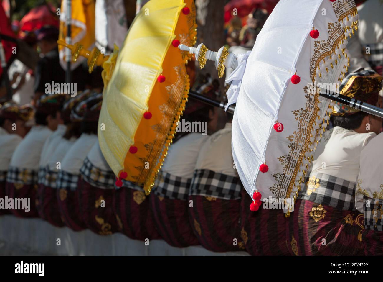 Jeunes hommes en costumes balinais sarong avec parapluies traditionnels payung. Cérémonie d'offrande religieuse hindoue. Arts et culture de l'île de Bali à Indones Banque D'Images