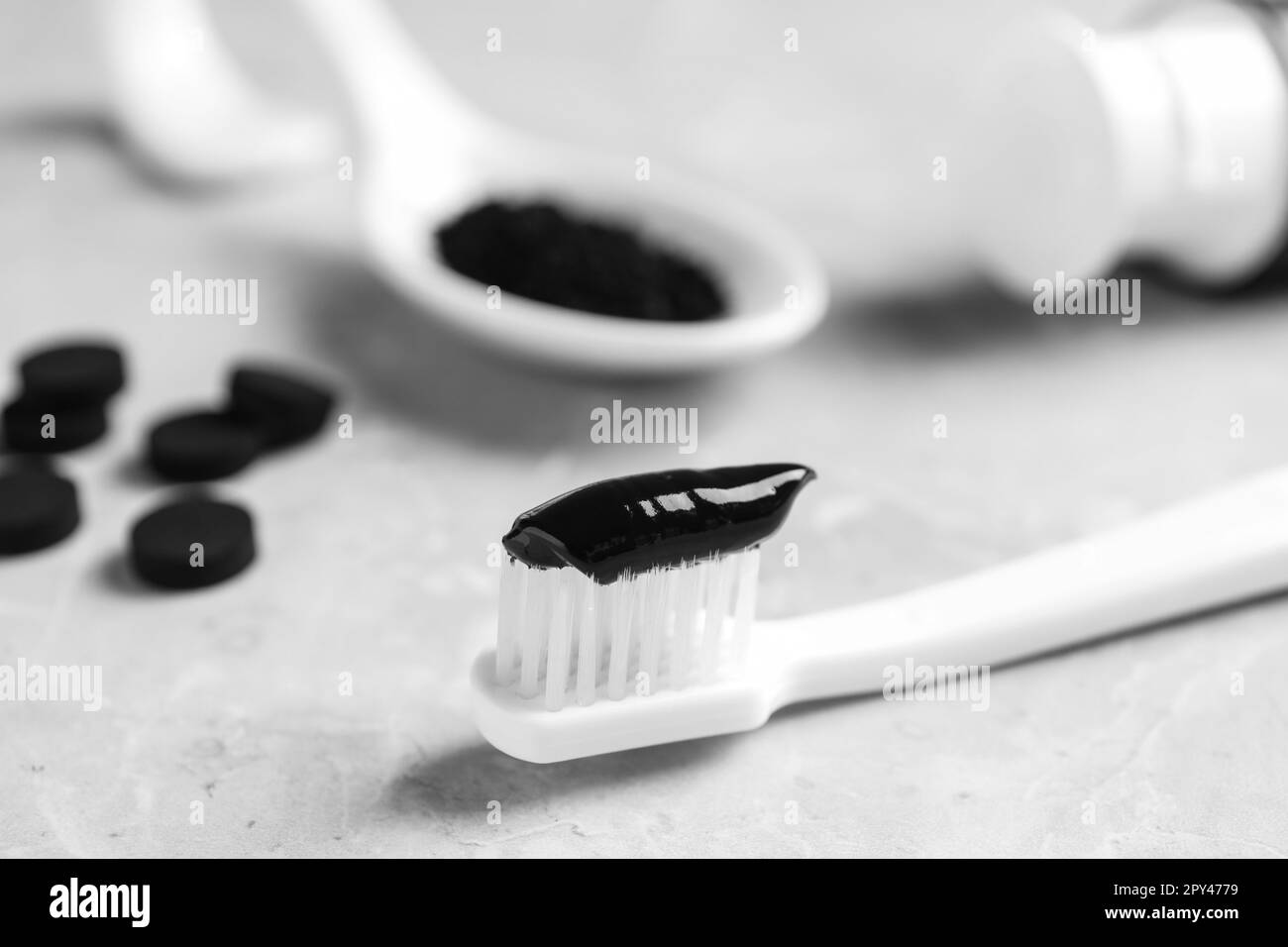 Badigeonner avec du dentifrice au charbon de bois sur une table gris clair, gros plan Banque D'Images