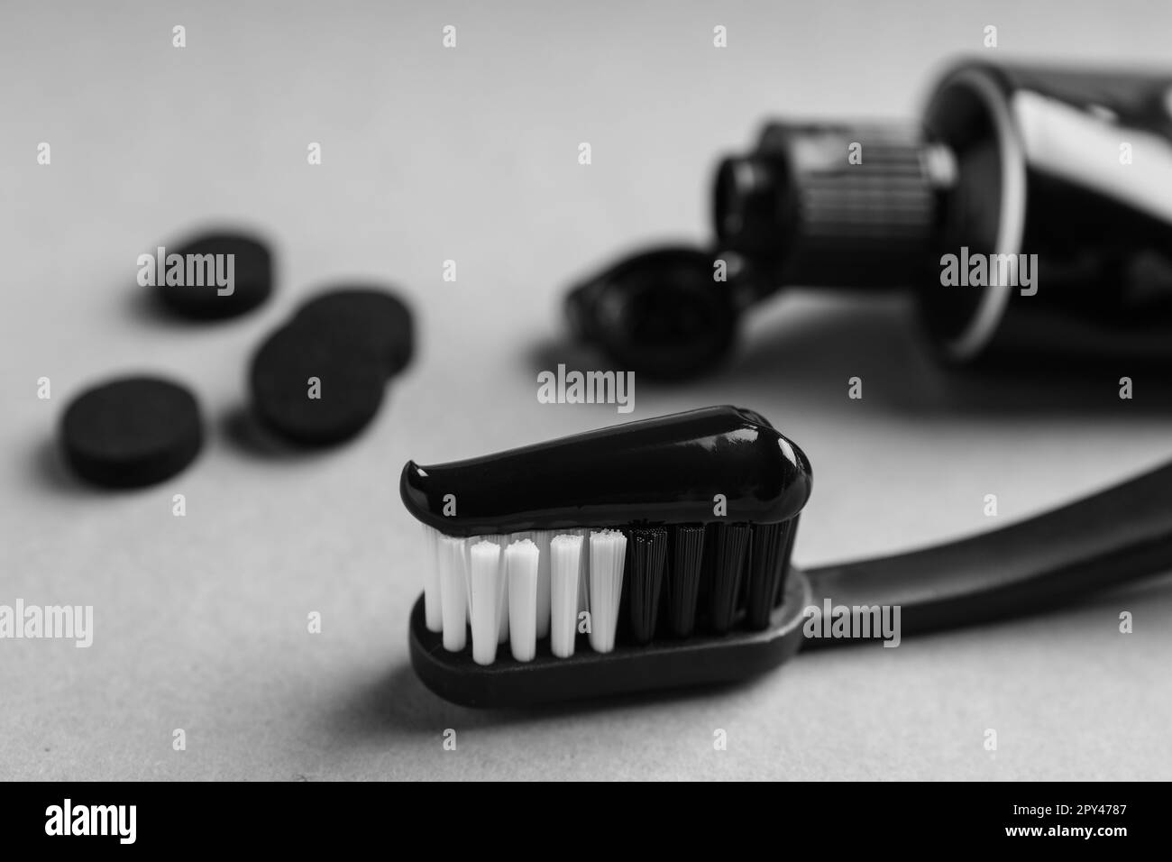 Brossez avec du dentifrice au charbon sur fond gris clair, gros plan Banque D'Images
