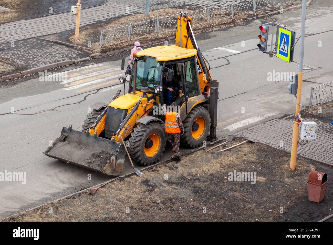 26.04.2023, Kemerovo, Russie. Un tracteur jaune est debout ou conduit sur la route pour les travaux sur route. Nettoyage de la rue avec un tracteur Banque D'Images