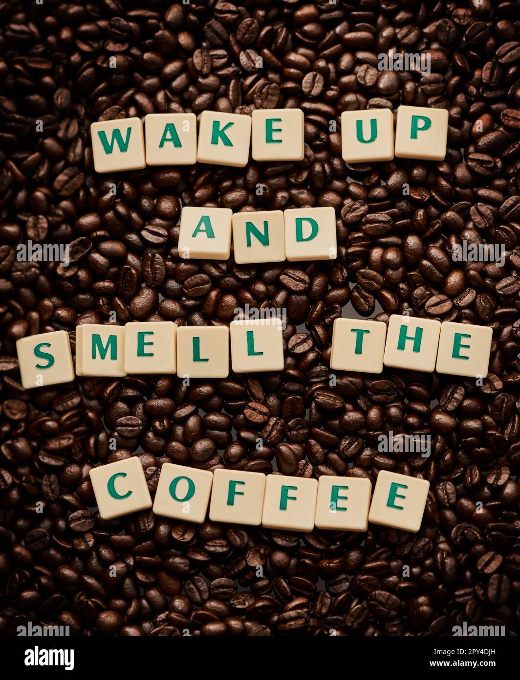 Laissez le café réveiller vos sens. Gros plan de lettres formant les mots se réveiller et sentir le café sur une pile de grains de café. Banque D'Images