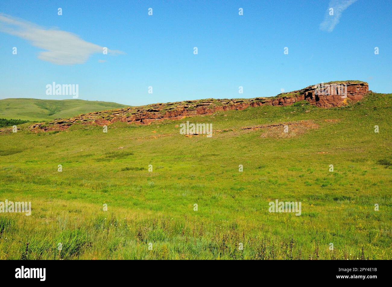 Vestiges d'un ancien mur de grès rouge ruiné qui remonte la pente jusqu'au sommet d'une colline douce et élevée par une journée d'été claire. Coffres de la chaîne de montagnes, Kha Banque D'Images
