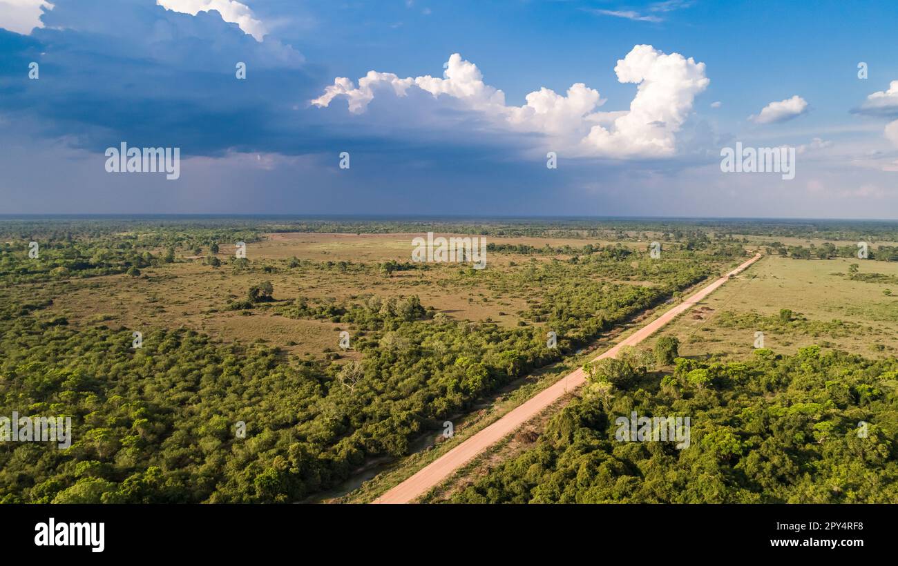 Vue aérienne avec les nuages de pluie un ciel bleu de Transpantaneira route de terre traversant les zones humides du Nord Pantanal, Mato Grosso, Brésil Banque D'Images