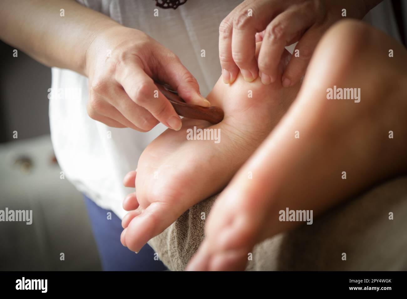 Client recevant un traitement de réflexologie d'acupression avec un bâton de massage à points en bois. Médecine naturelle, réflexologie, massage des pieds d'acupression Banque D'Images