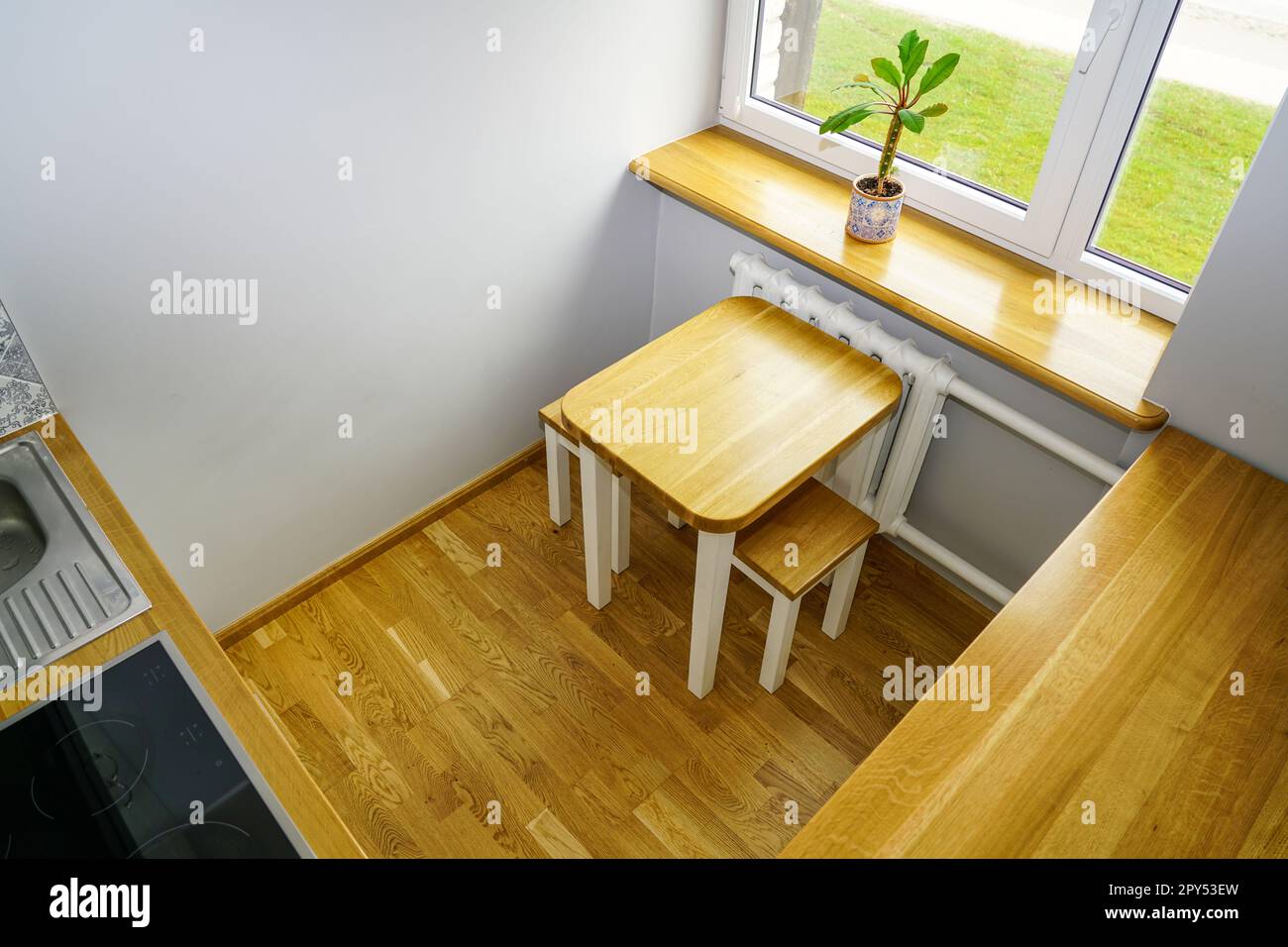 Très petite et confortable salle de cuisine avec plancher en bois naturel, seuil de fenêtre et surfaces de meubles, vue d'en haut Banque D'Images