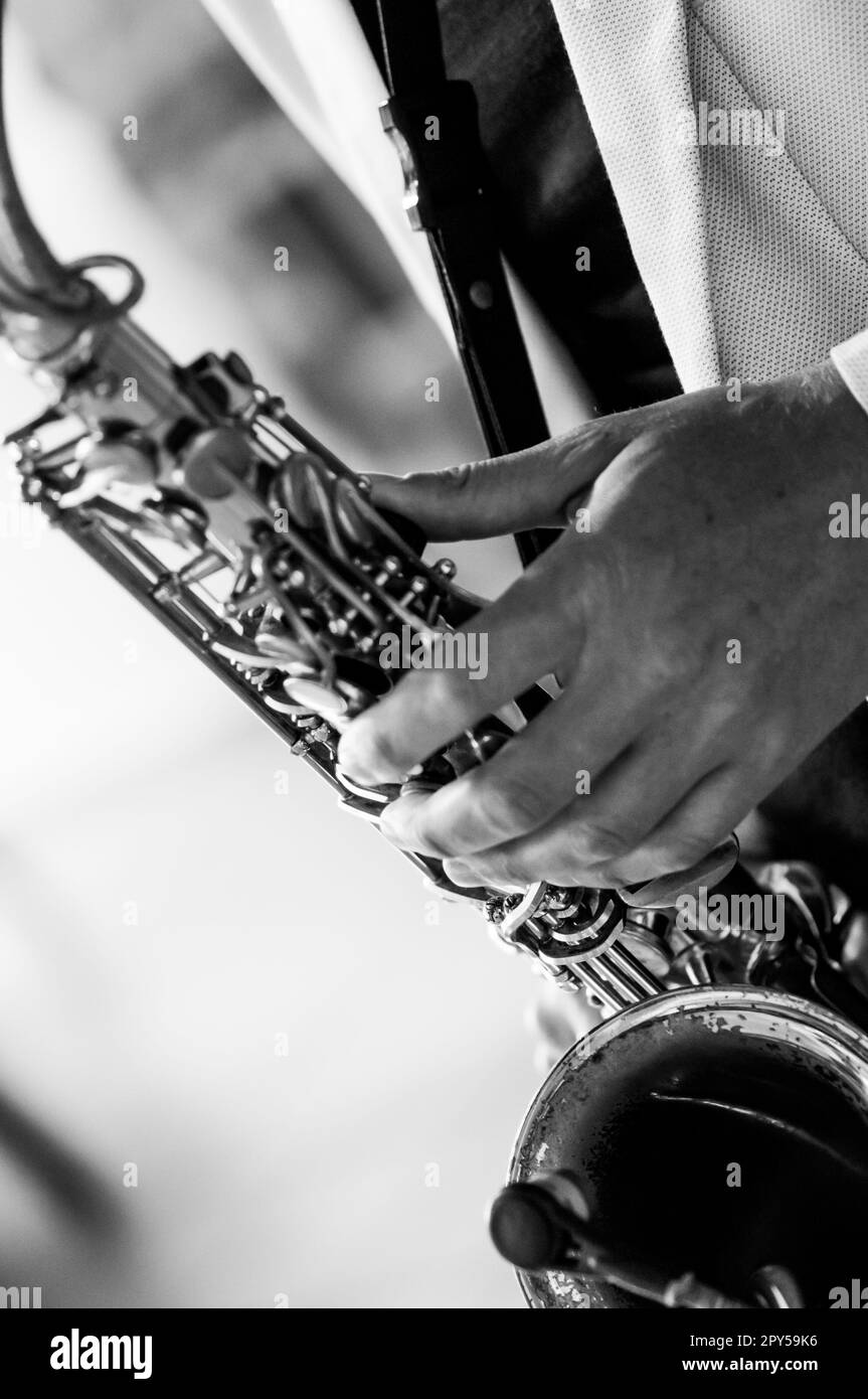 Mains d'homme avec saxophone sur fond bordeaux. Photographie en noir et blanc Banque D'Images