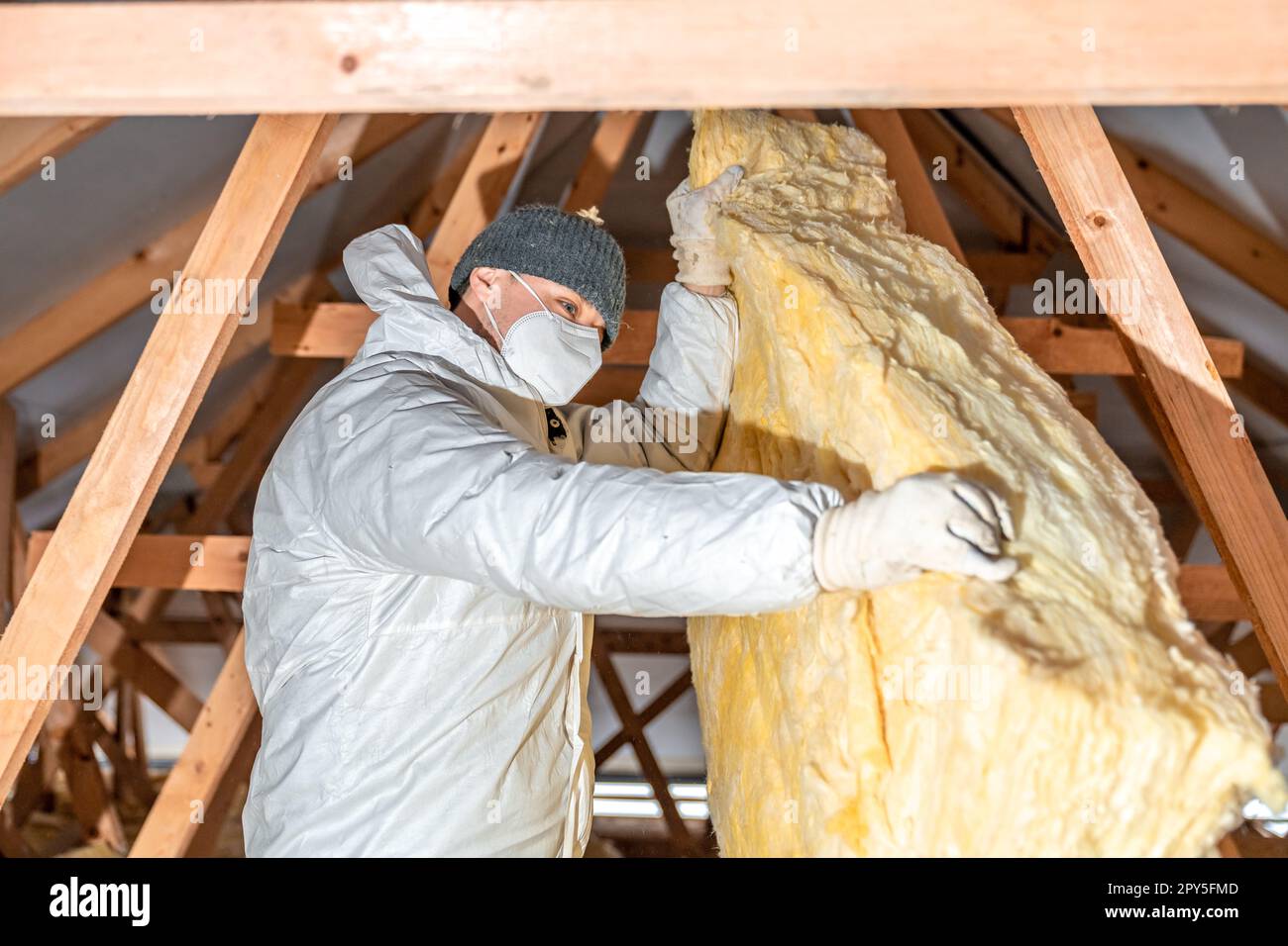 l'homme isole le toit et le plafond de la maison avec de la laine de verre Banque D'Images