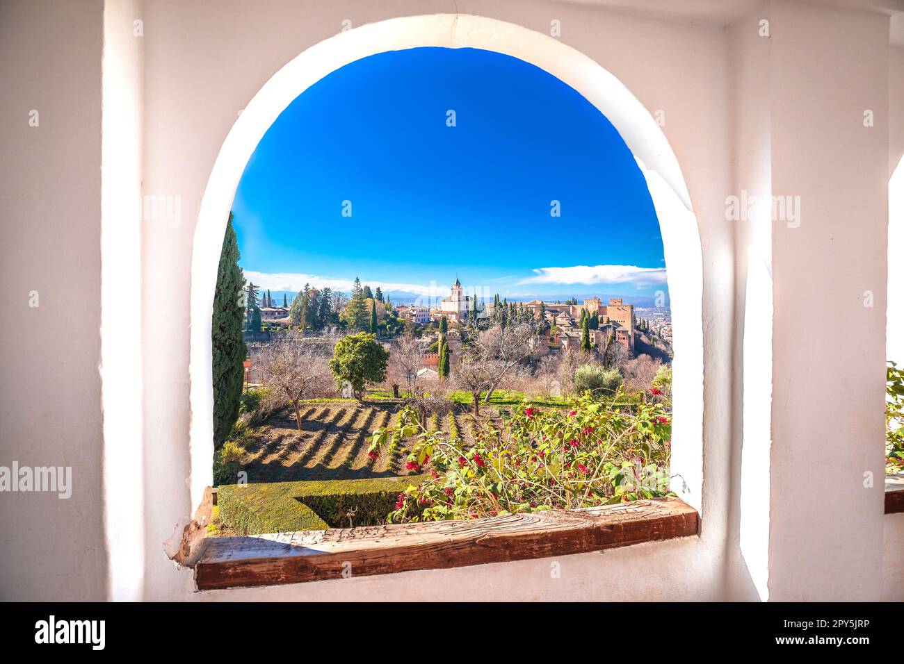 Vue sur l'Alhambra antique à travers une fenêtre en pierre, site classé au patrimoine mondial de l'UNESCO à Grenade, région andalouse de l'Espagne Banque D'Images