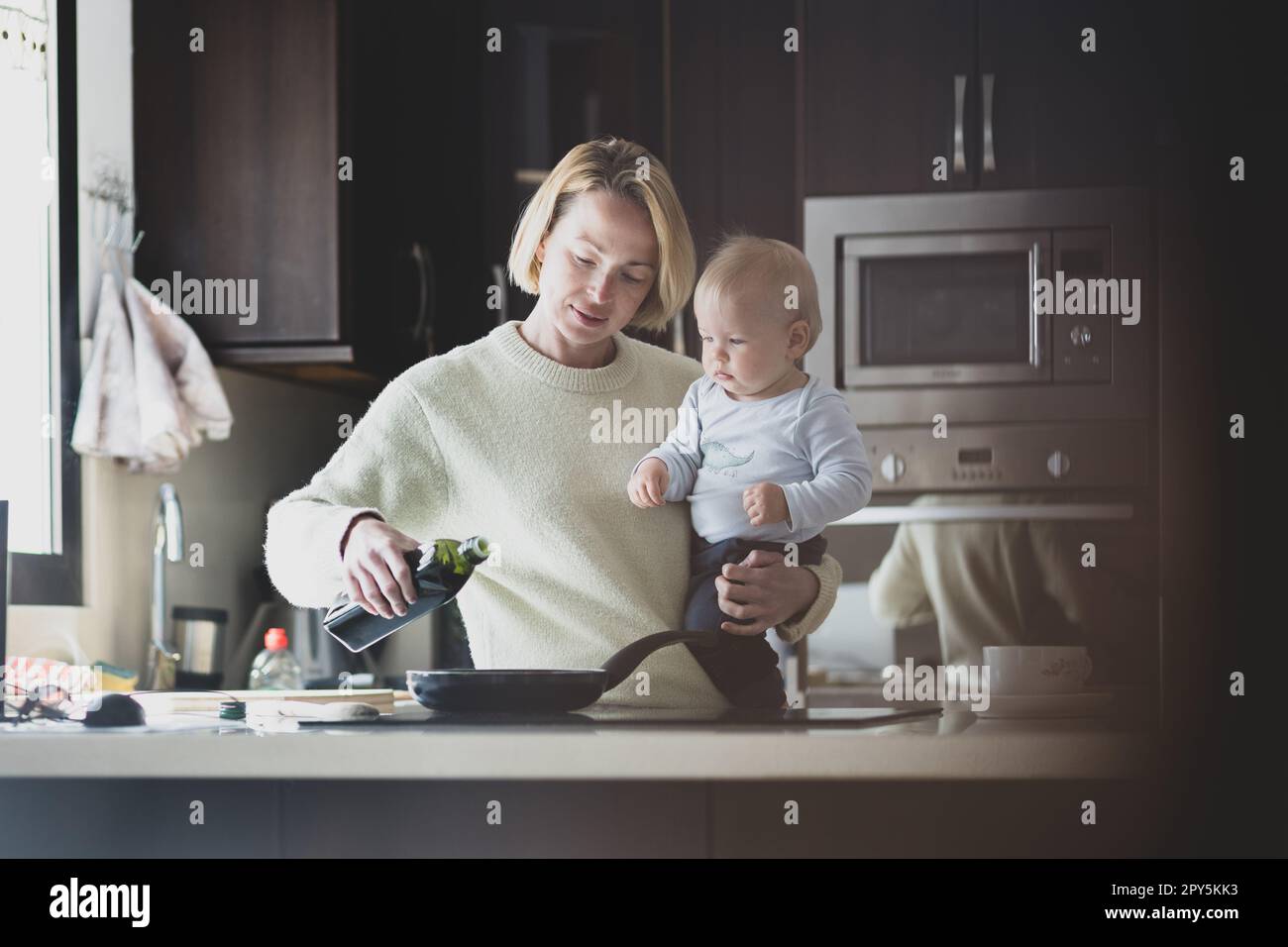 Une mère heureuse et un petit garçon bébé font ensemble des crêpes pour le petit déjeuner dans la cuisine. Famille, mode de vie, vie domestique, nourriture, alimentation saine et concept de personnes. Banque D'Images