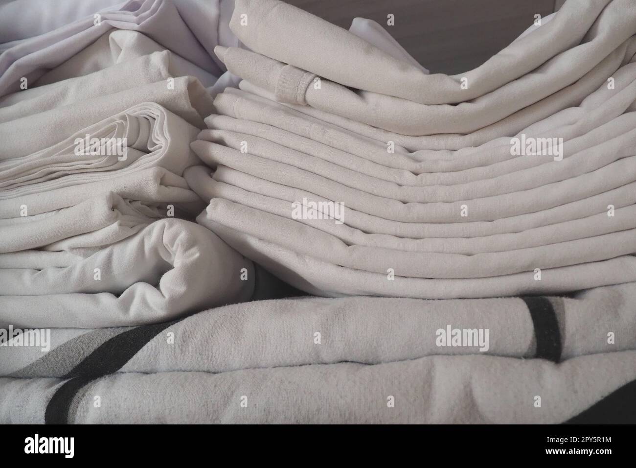 Les draps blancs sont empilés dans le placard. Contenu interne d'une armoire à linge. Organisation du ménage. Conditions d'hygiène pour le sommeil. Tissus et draps dans un placard ou une armoire blanc à moitié ouvert Banque D'Images