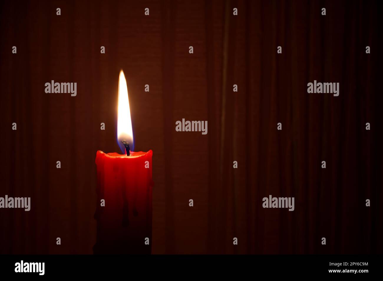 Bougie rouge allumée sur fond rouge foncé Banque D'Images