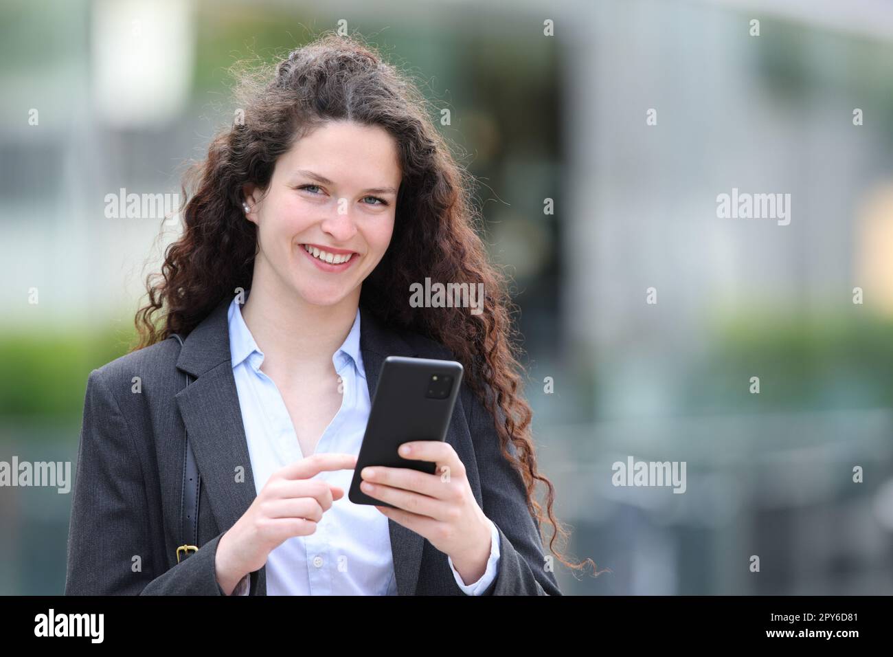 Femme d'affaires qui vous regarde avec un smartphone Banque D'Images