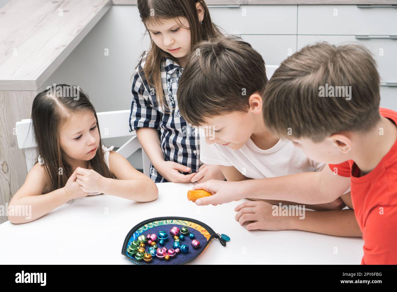 Un groupe d'amis joue à la pêche en jouet sur une table. Les enfants tiennent la canne à pêche et ramassent des articles de jeu en métal coloré de l'assiette. Banque D'Images