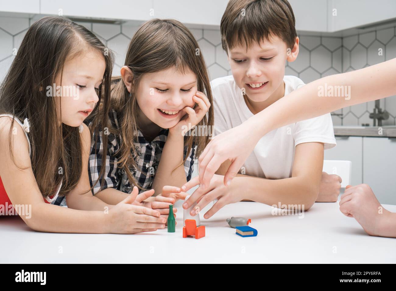 Bonne petite école les enfants jouent jouet mini meubles sur la table de cuisine. Groupe d'amis tenant de petites jouets en plastique. Banque D'Images