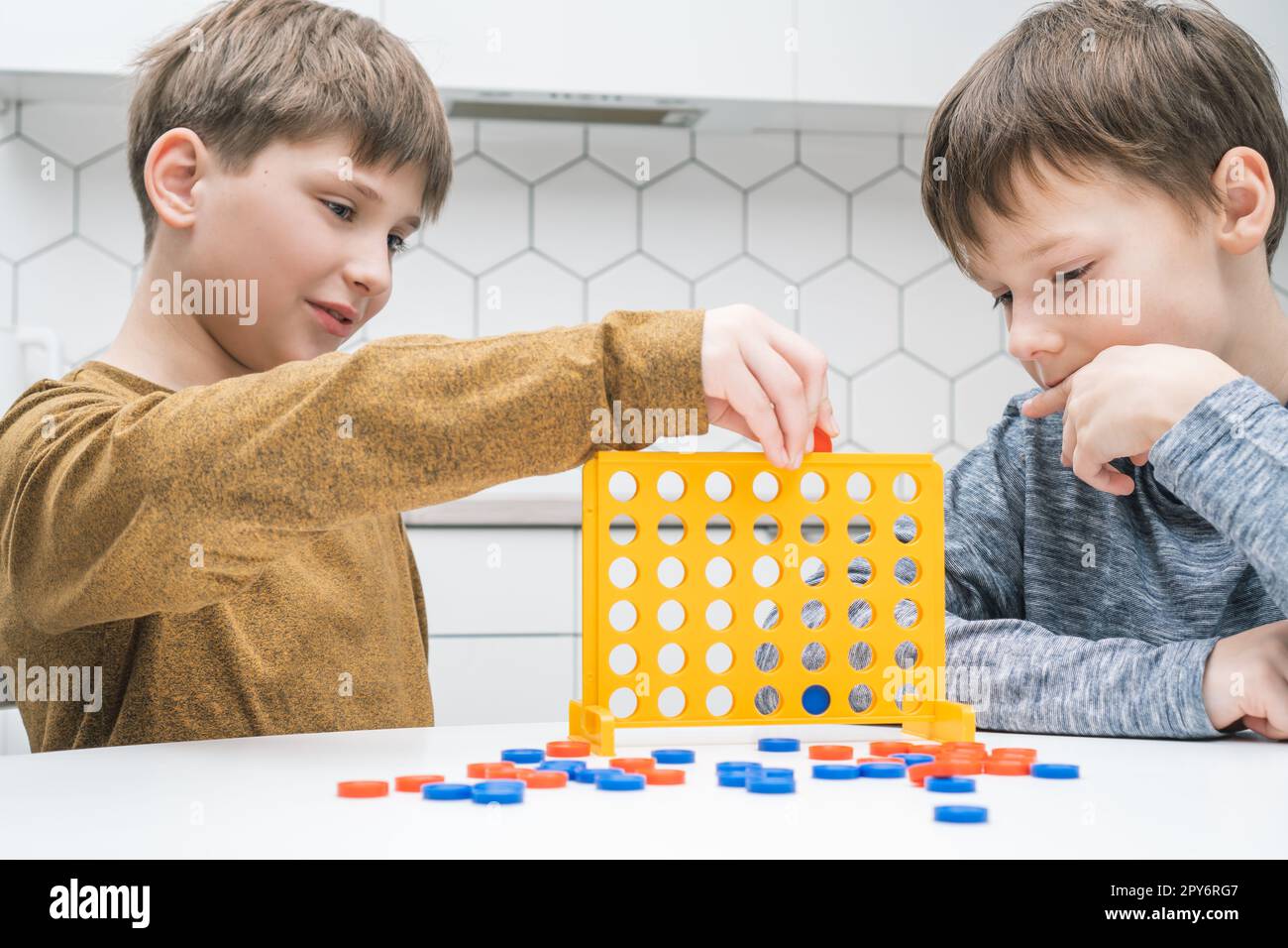 Les adorables écoliers jouent jouet constructeur assis à la table de cuisine. Les enfants collectent les détails en plastique de lego. Banque D'Images